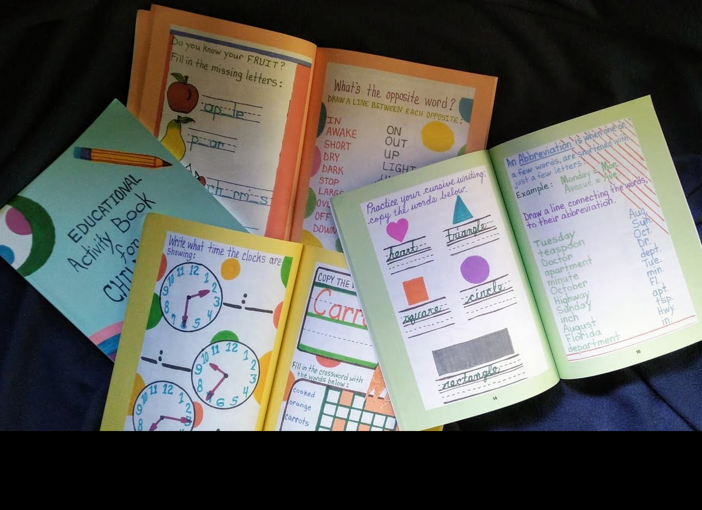 Open activity book pages — fruit, opposites, clocks, and cursive practice
